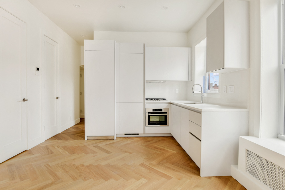 A kitchen with white cabinets and a wooden floor.